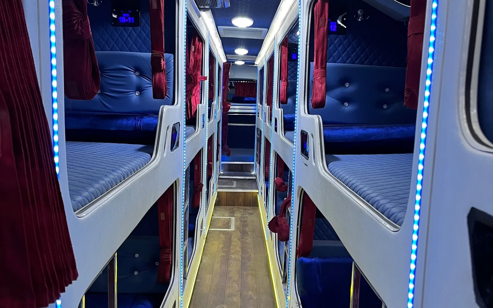 Sleeper cabin: white berth pods with blue quilted mattresses and red curtains